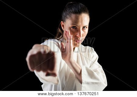 Female fighter performing karate stance on black background
