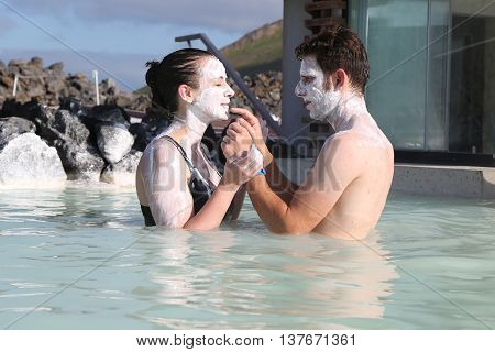 ICELAND - JULY 5, 2016: Geothermal spa visitors with silica mud masks relax and refresh at the famous Blue Lagoon in Iceland