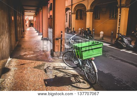 Bologna Italy April 25 2016: parked bicycle on narrow street along an empty portico