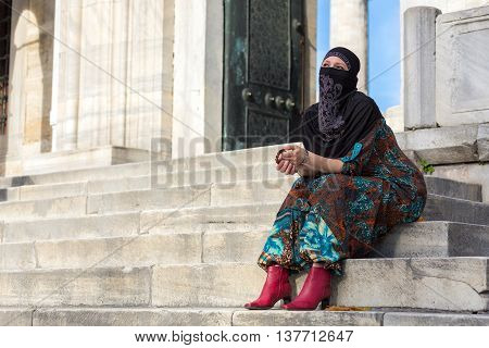 Muslim Style dressed Lady sitting on Marble Steps of Blue Mosque of Istanbul City Pensive look holding Rosary