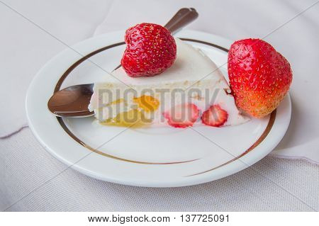 a piece of dessert with strawberries and cream on a plate with a spoon