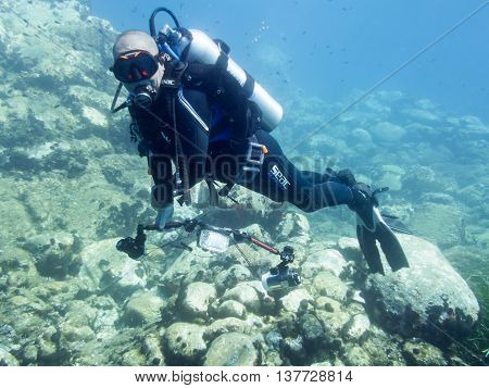 Avlaki Greece - June 15 2016 : A male scuba diver with a camera shows good buoyancy during a dive