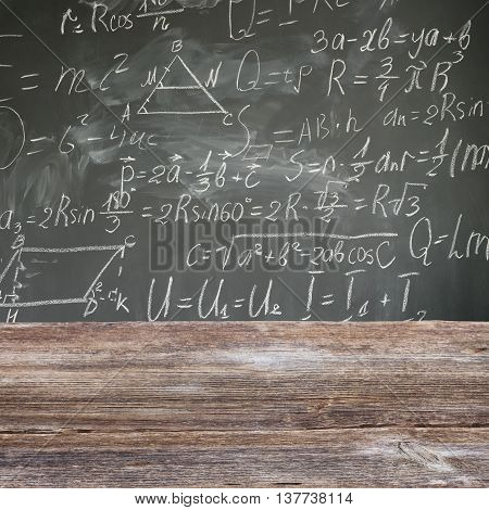 school desk with math formulas written in white chalk on black board background