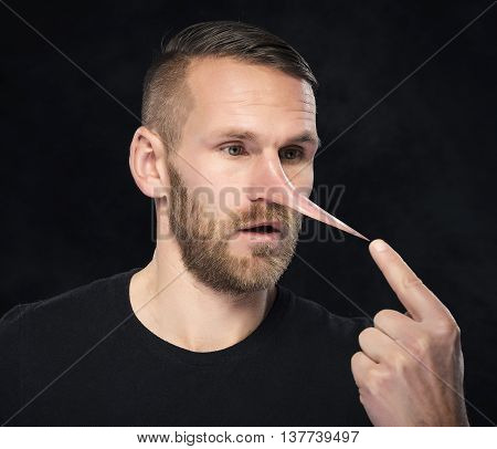 Man with a nose like Pinocchio on dark backgrond.
