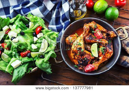 Grilled chicken legs lettuce and cherry tomatoes limet olives. Traditional cuisine. Mediterranean cuisine.