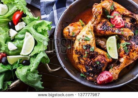 Grilled chicken legs lettuce and cherry tomatoes limet olives. Traditional cuisine. Mediterranean cuisine.