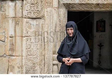 TBILISI GEORGIA - CIRCA JULY 2016: a nun at a door of an old Ananuri monastery