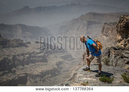 JEBEL SHAMS, OMAN - CIRCA AUGUST, 1015: a hiker is looking over an open ledge into a canyon on the way up the highest peak in Oman called Jebel Shams