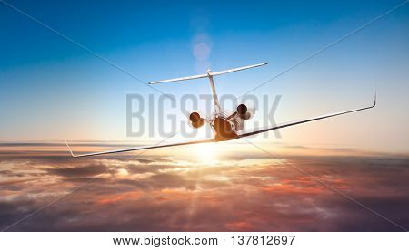 Private jet plane flying above clouds in beautiful sunset. Shot from front view