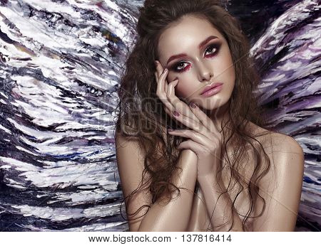 One pretty tender dreaming young fashionable woman with long curly hair bright makeup and with angel wing behind