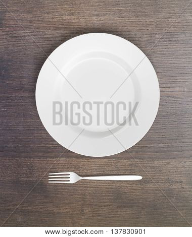 Top view of empty plate and fork on dark wooden table. Mock up 3D Rendering