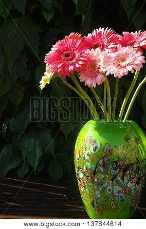 Colorful gerbera daisies in green vase made from mozaic murano glass