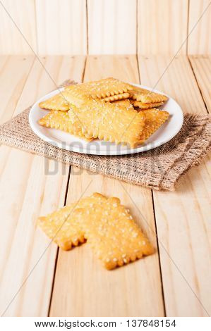 Stacked butter biscuits with sesame in white plate on wooden background