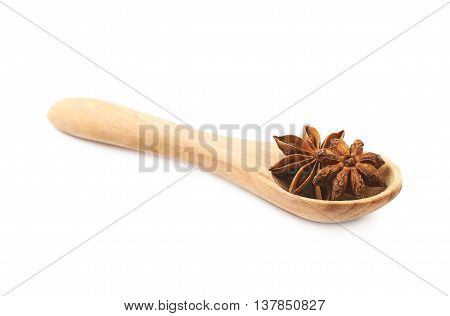 Chinese star anise seed served in a wooden spoon, composition isolated over the white background