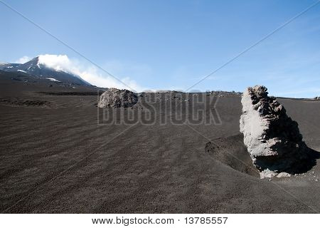 Grote vulkanisch gesteente met Etna berg In achtergrond, Sicilië, Italië