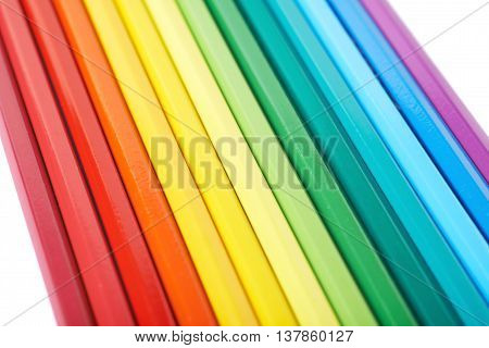 Multiple colorful color pencils composition arranged in a line to form a rainbow gradient, composition isolated over the white background, close-up crop fragment