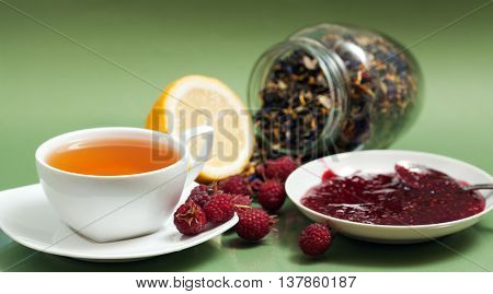 Tea lemon jam and red raspberry berries on a green