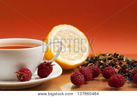 Tea lemon and red raspberry berries on a orange background