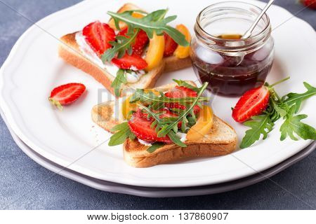 French toast with fresh strawberries, peaches and arugula, poured with maple syrup