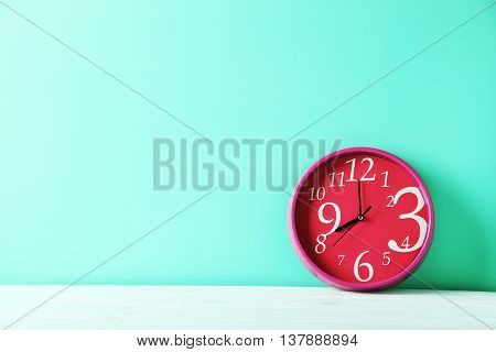 Pink round clock on a green wooden table
