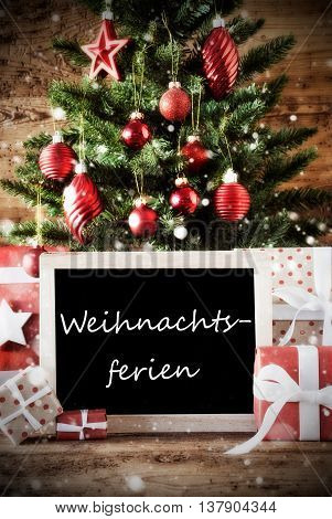 Christmas Card For Seasons Greetings. Christmas Tree With Balls. Gifts Or Presents In The Front Of Wooden Background. Chalkboard With German Text Weihnachtsferien Means Christmas Break