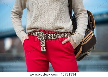 Fashionable women`s casual spring outfit with red pants cardigan modern belt and shoulder bag