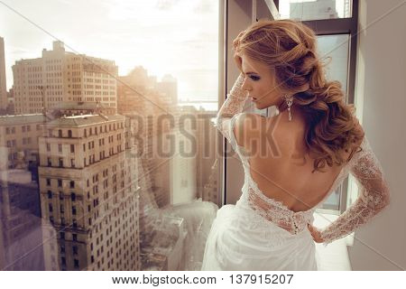 Beautiful Young bride in wedding dress posing near window