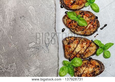 Baked eggplant stuffed with vegetables and cheese with addition aromatic herbs and sauce on paper. Delicious vegetarian dish. top view, sopy space