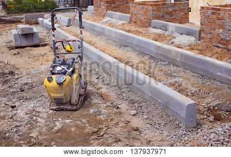vibratory plate compactor at a construction site. small gasoline single direction plate compactor at the construction of the entrance to the building. Asphalt paving machine