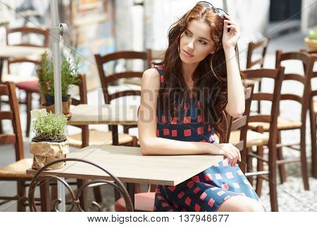 Stylish  woman, wearingsummer dresst,  posing at city cafe terrace, traveling clone, sunny day.