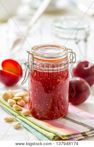 A jar of homemade plum jam with almonds. Delicious healthy breakfast.
