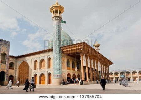 SHIRAZ, IRAN - OCT 21, 2014: Old mosque Shah Cheragh with minaret and prayers walking around on October 21, 2014. Famous pilgrimage centre for shia muslims from the 14th century