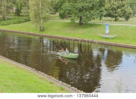 RIGA LATVIA - JUNE 29 2016: Rest on the water - young couple boating at city canal in the historic center of Riga Latvia. Canal was made instead of former fortification walls