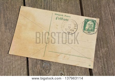 old blank vintage postcard with old stamp is on old wood