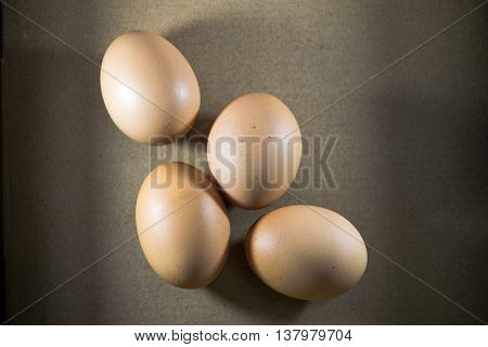 Four fresh  eggs on a brown background.