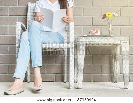 Woman sitting on wood weave chair in house for reading a white book in free time in the afternoon relax time and lifestyle of asian woman concept