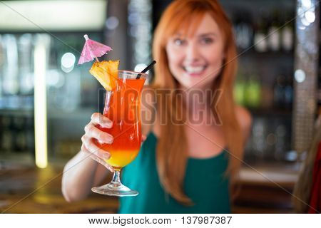 Portrait of happy woman holding a cocktail glass at bar counter in bar