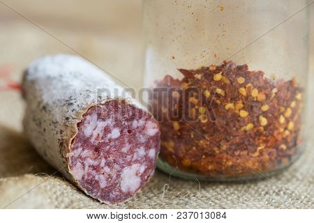 Piece Of Hot Salami Near A Glass Bowl Of Hot Crushed Chilli