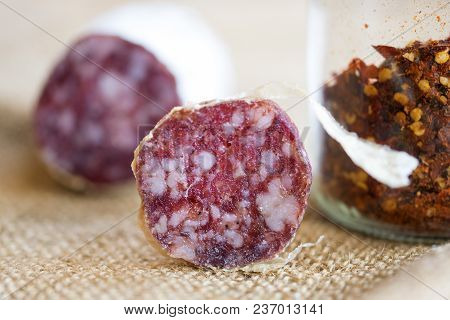 Slice Of Hot Salami With Crushed Hot Pepper On A Background