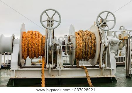 Winch With Orange Rope On A Ferry, White Cloudy Backgrond.