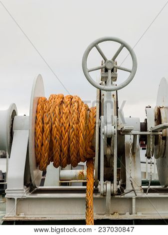 Winch With Orange Rope On A Ferry, White Cloudy Backgrond.