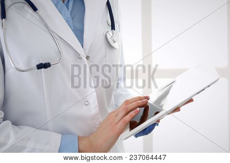 Woman Doctor Using Tablet Computer While Standing Straight In Hospital Closeup. Healthcare, Insuranc