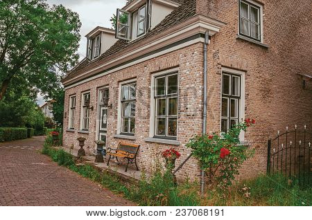 Charming And Quiet Alley With Brick Rustic Houses And Greenery In Cloudy Day At Drimmelen. A Lovely 