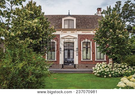 Drimmelen, Southern Netherlands - June 30, 2017. Charming Brick Rustic House With Flowered Garden An