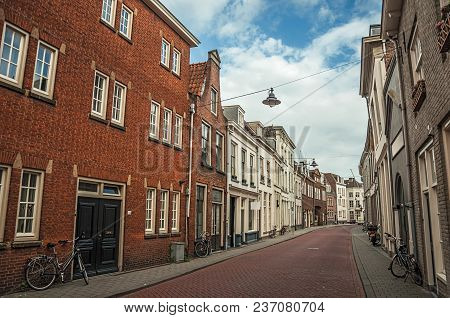 Empty Street With Semidetached Brick Houses And Bicycles In Front Of Doors At Sunset And Blue Cloudy