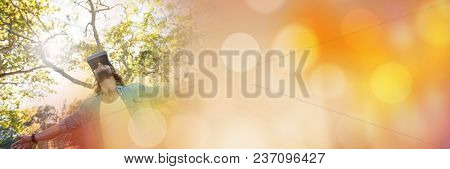 Low angle of man in virtual reality headset embracing forest with orange bokeh transition