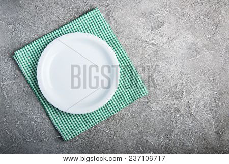 Empty White Plate With Nupkin On A Gray Stone Background