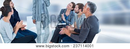 Group of People sitting in circle with ladt standing up and clapping hands