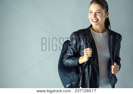 portrait of beautiful young brunette woman in stylish black jacket on gray.