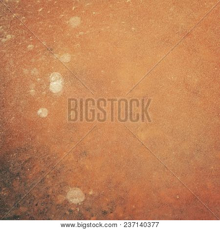 Layer Of Ice Over An Orange Clay Soil. Natural Texture. Spring In Russia. Frozen Puddle Texture. Ton